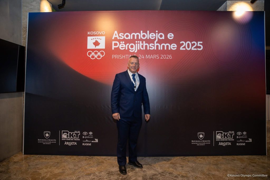 Një burrë me kostum para panos “Asambleja e Përgjithshme 2025”.