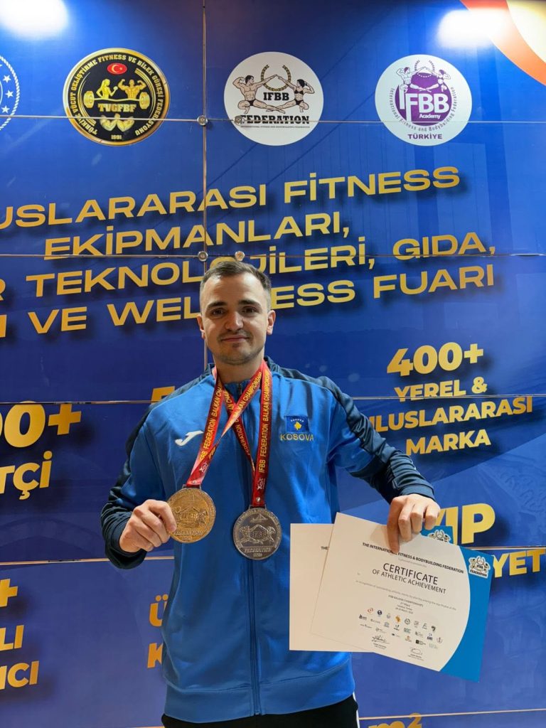 Takmičar sa medaljom i diplomom ispred banera sajma.