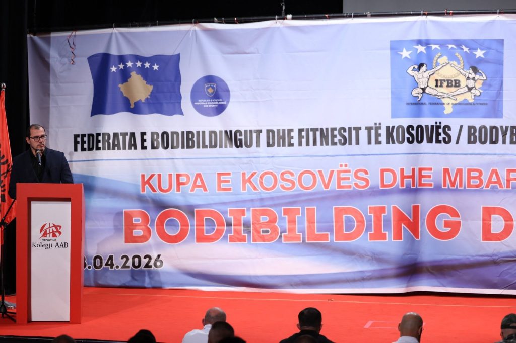 Një burrë duke folur në foltore para banerit të Kupës së Kosovës.