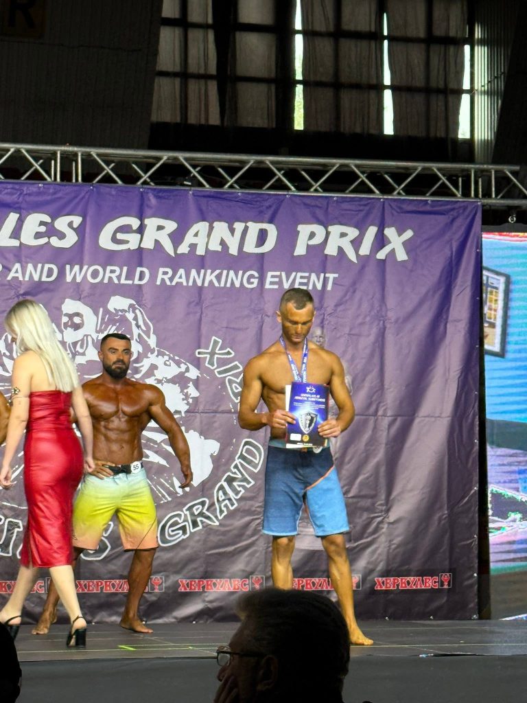 Garues të Men’s Muscular në skenën e Herkules Grand Prix, njëri me çmim në dorë.